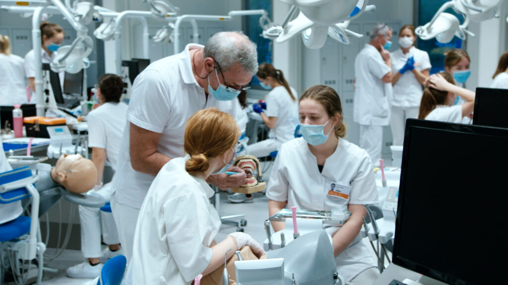 Docent en studenten in tandheelkunde praktijkles